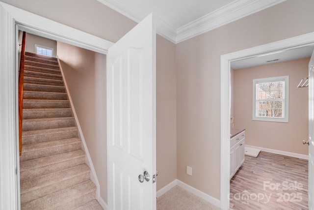 stairway with crown molding, baseboards, and wood finished floors