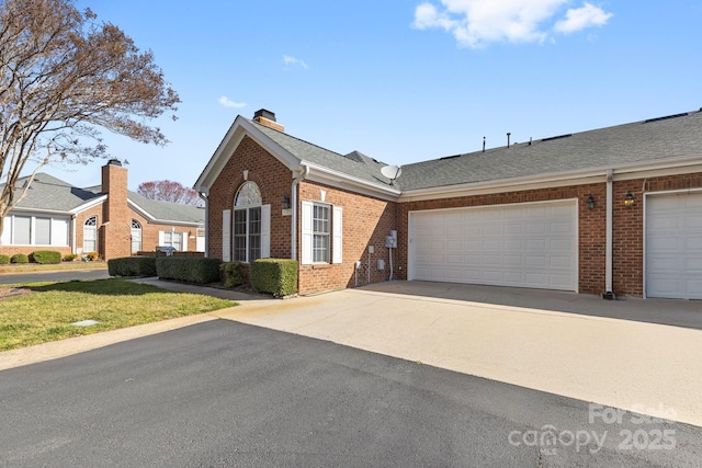 view of front facade with concrete driveway, a chimney, roof with shingles, an attached garage, and brick siding