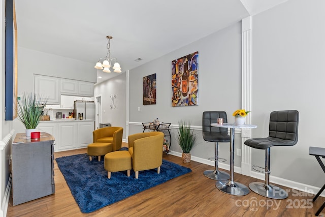 living area with light wood-type flooring, baseboards, visible vents, and a chandelier