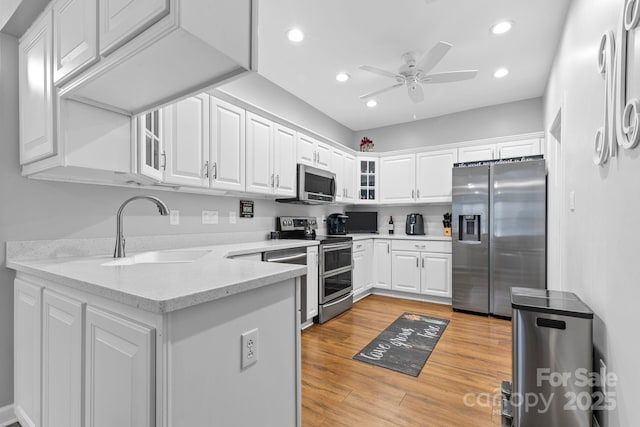 kitchen with stainless steel appliances, a sink, glass insert cabinets, and white cabinets