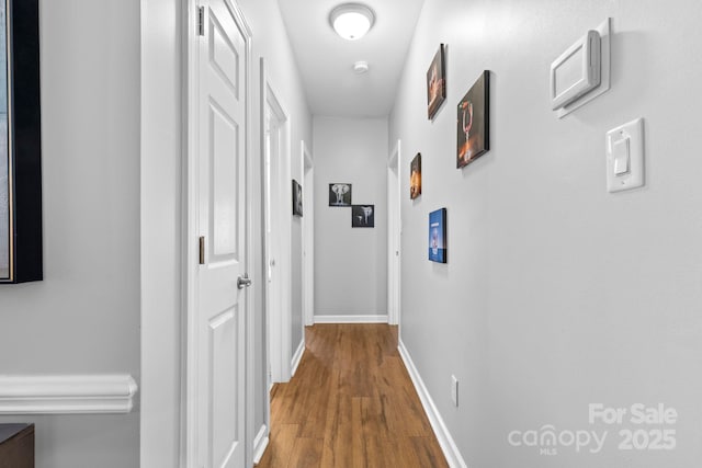 hallway featuring baseboards and wood finished floors