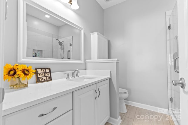 full bath featuring toilet, a shower stall, vanity, wood finished floors, and baseboards