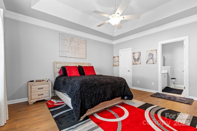 bedroom with a tray ceiling, wood finished floors, and baseboards