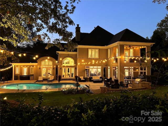 rear view of house featuring a balcony, outdoor lounge area, french doors, a chimney, and a patio area