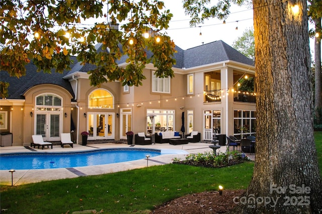 rear view of property with french doors, stucco siding, outdoor lounge area, a patio area, and an outdoor pool