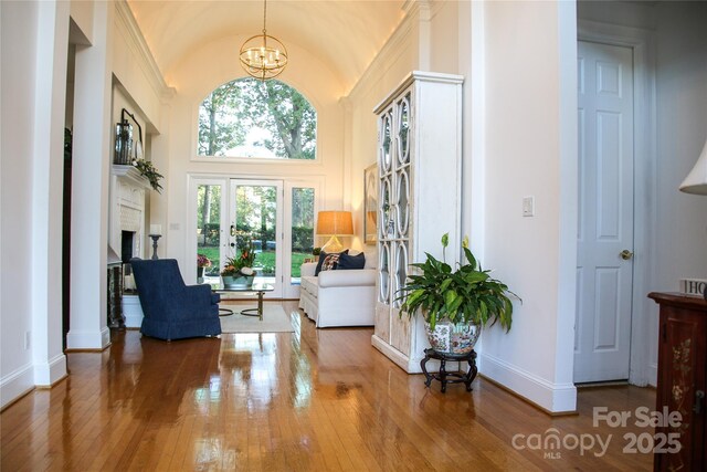 sitting room featuring lofted ceiling, baseboards, hardwood / wood-style floors, and an inviting chandelier