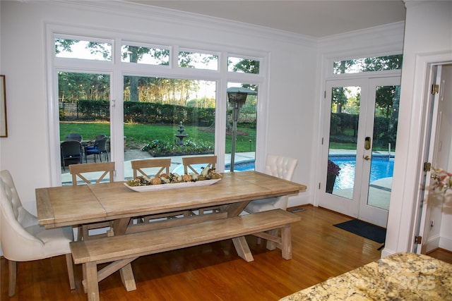 dining space featuring ornamental molding, wood finished floors, and french doors