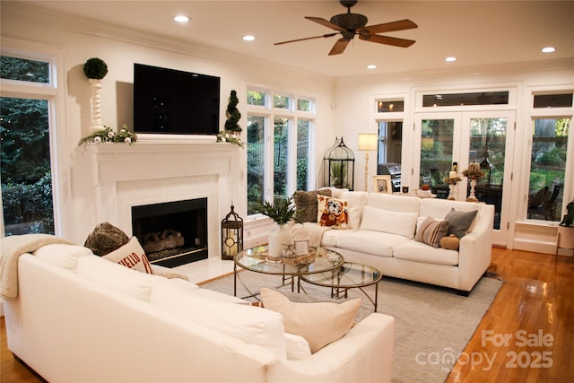 living area featuring recessed lighting, a fireplace, crown molding, and wood finished floors