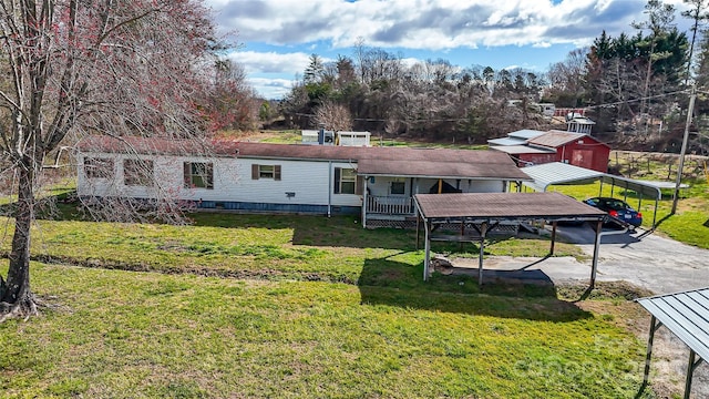 rear view of property featuring a yard, a carport, and driveway