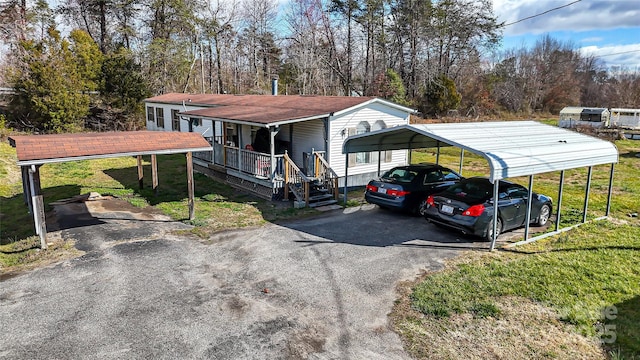 view of front of home with a detached carport, covered porch, driveway, and a front lawn