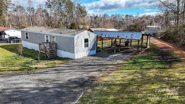 exterior space featuring aphalt driveway, a front yard, and a carport