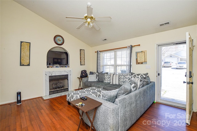 living room with a high end fireplace, visible vents, lofted ceiling, wood finished floors, and a ceiling fan