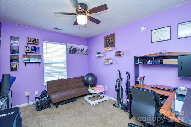 carpeted office space featuring a textured ceiling, baseboards, visible vents, and ceiling fan