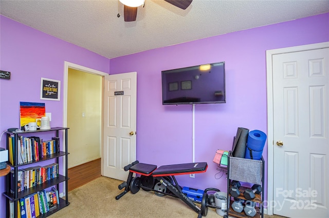 workout room with carpet flooring, a textured ceiling, and a ceiling fan