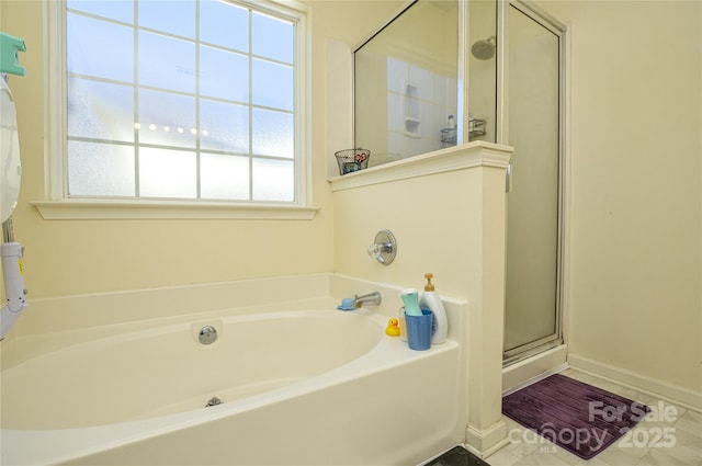 bathroom featuring baseboards, a garden tub, and a shower stall