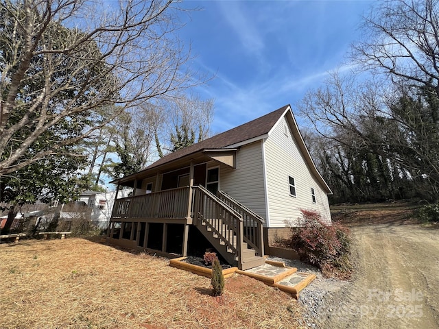 view of front of property with roof with shingles, stairs, and a wooden deck