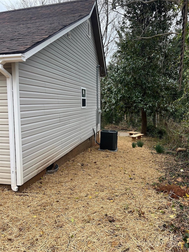 view of property exterior with a shingled roof and central AC unit