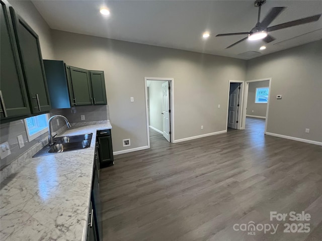 kitchen with decorative backsplash, dark wood-type flooring, a sink, light countertops, and green cabinetry