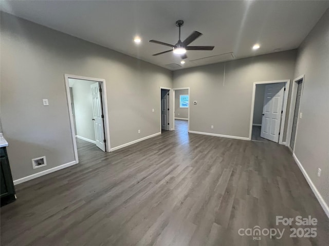 interior space featuring dark wood-type flooring, a walk in closet, attic access, and baseboards