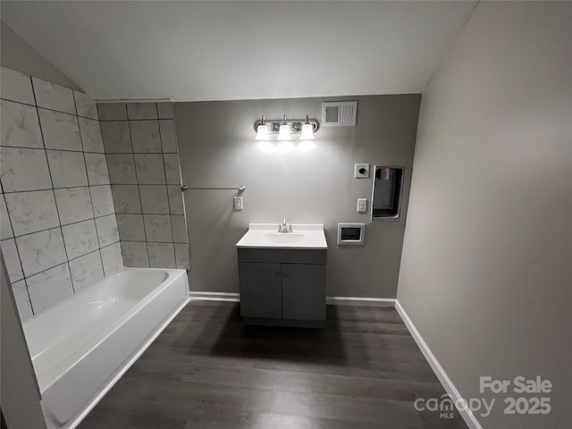 bathroom featuring wood finished floors, vanity, visible vents, vaulted ceiling, and baseboards