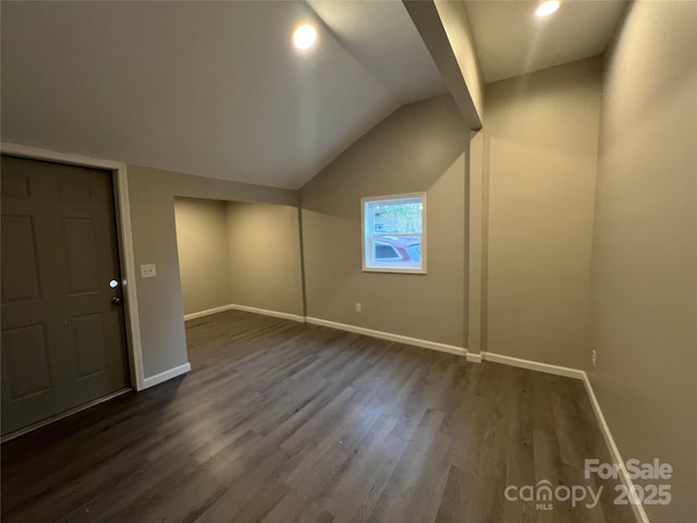 interior space featuring lofted ceiling, dark wood finished floors, and baseboards