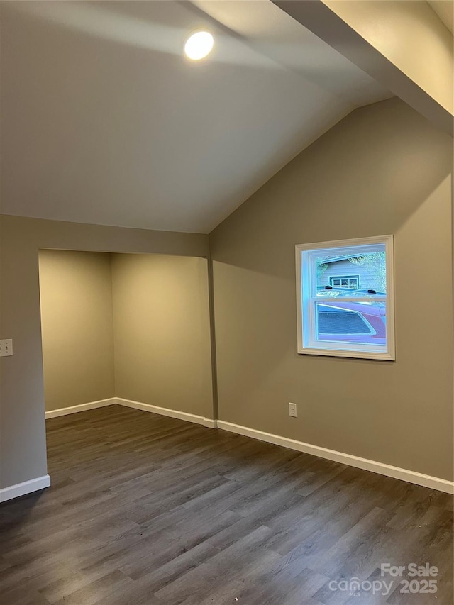 interior space with vaulted ceiling, dark wood-style flooring, and baseboards