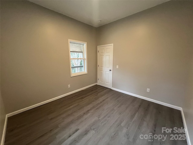 spare room with dark wood-style floors and baseboards