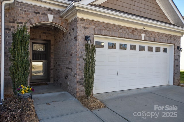 property entrance featuring concrete driveway and brick siding