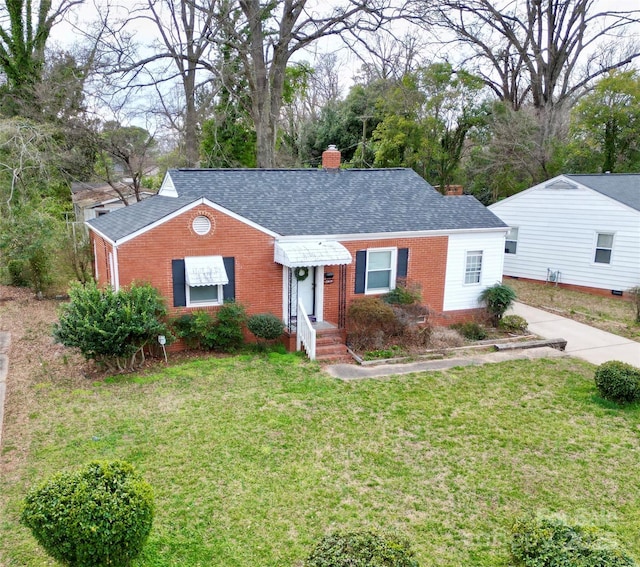 ranch-style house featuring a shingled roof, a chimney, a front lawn, and brick siding