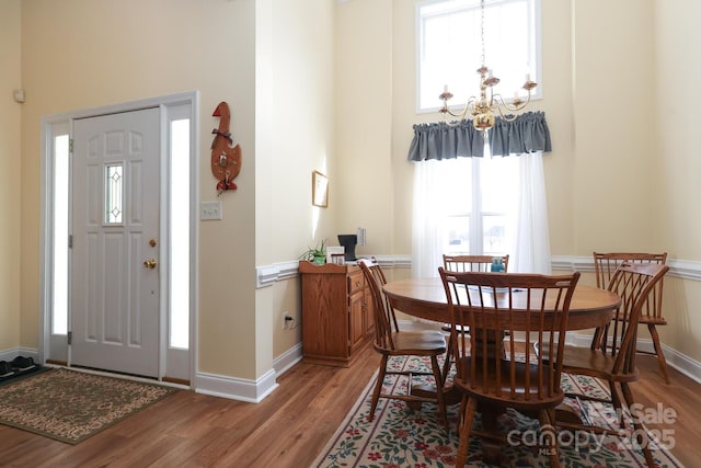 entryway with a chandelier, baseboards, light wood-style flooring, and a towering ceiling