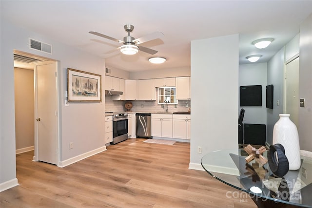 kitchen featuring light wood-style flooring, under cabinet range hood, stainless steel appliances, visible vents, and white cabinets