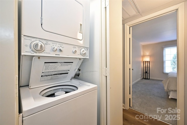 laundry area featuring laundry area, carpet floors, stacked washer and clothes dryer, and baseboards