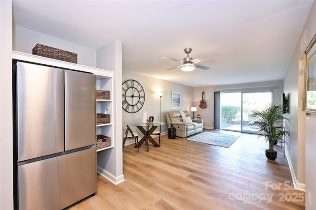 living area with ceiling fan, light wood-type flooring, and baseboards