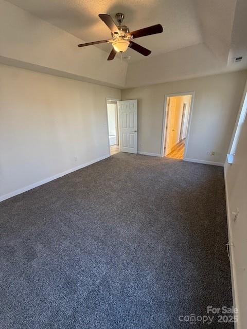 unfurnished bedroom with carpet floors, baseboards, a tray ceiling, and ceiling fan