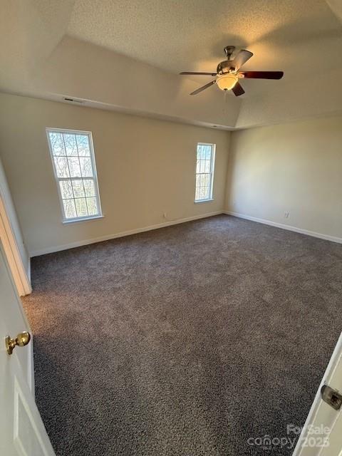 empty room with dark carpet, a textured ceiling, baseboards, and ceiling fan