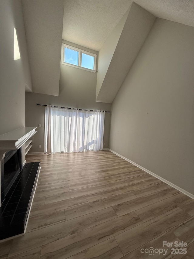 unfurnished living room with a tile fireplace, a textured ceiling, and wood finished floors