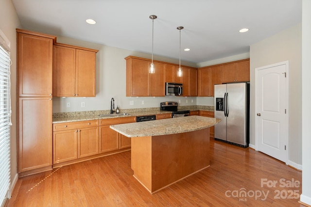 kitchen with appliances with stainless steel finishes, a kitchen island, light wood-type flooring, and a sink