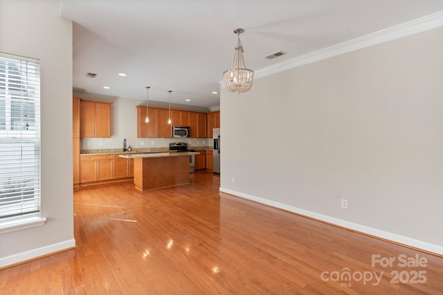 kitchen with a center island, light wood finished floors, stainless steel appliances, visible vents, and baseboards