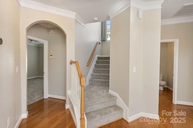 stairway featuring crown molding, visible vents, arched walkways, and wood finished floors