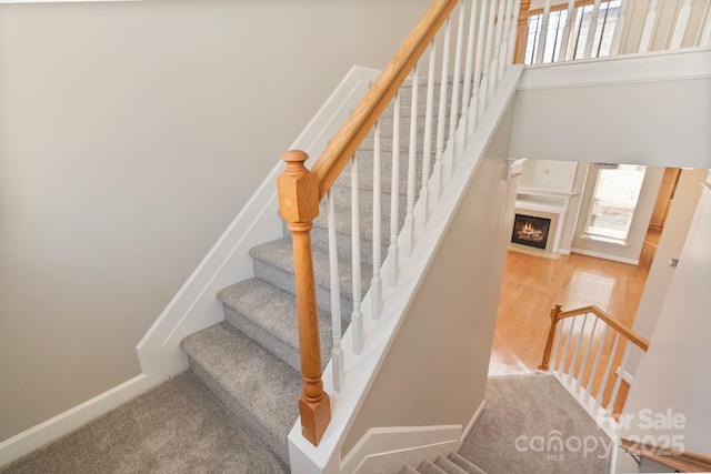 stairs with a fireplace with flush hearth and baseboards