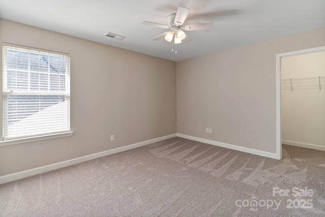 unfurnished bedroom featuring baseboards, a spacious closet, visible vents, and light colored carpet