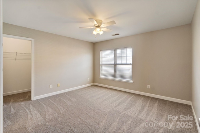 unfurnished bedroom with carpet floors, visible vents, baseboards, a closet, and a walk in closet