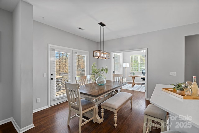 dining area with a chandelier, visible vents, dark wood-type flooring, and baseboards