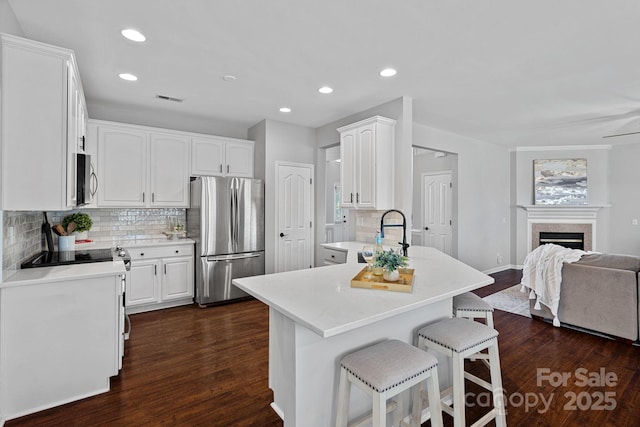 kitchen with a sink, open floor plan, appliances with stainless steel finishes, a breakfast bar area, and a peninsula