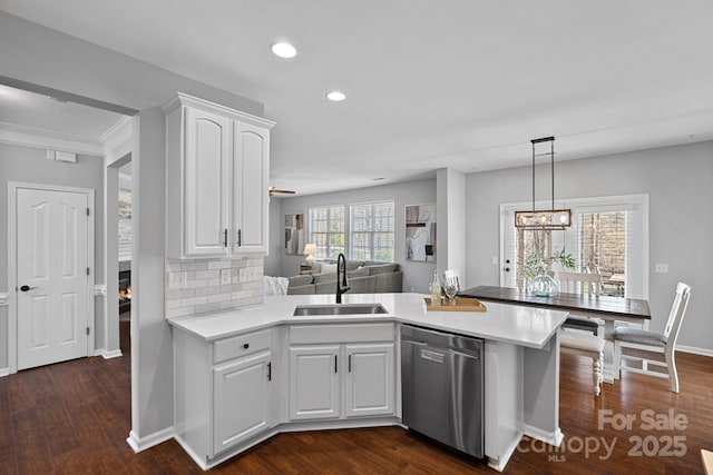 kitchen featuring a sink, a peninsula, white cabinetry, and stainless steel dishwasher