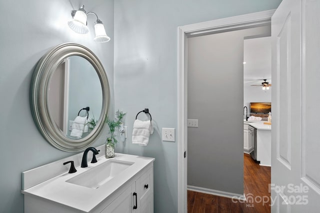 bathroom with baseboards, a ceiling fan, wood finished floors, and vanity