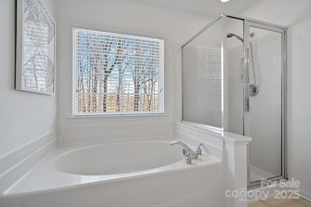 full bathroom with a shower stall and a bath