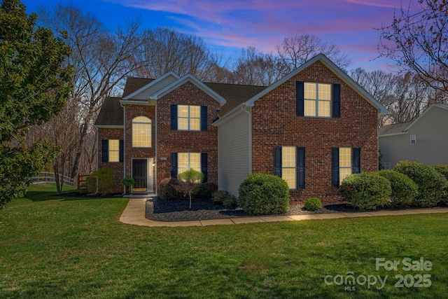 traditional-style house with brick siding and a front lawn