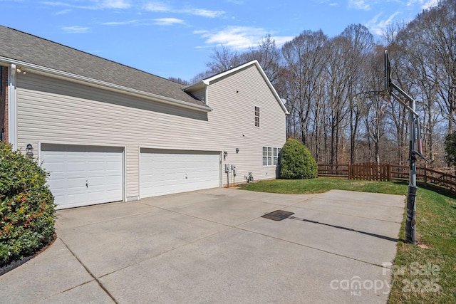 view of side of property featuring a lawn, roof with shingles, driveway, and fence