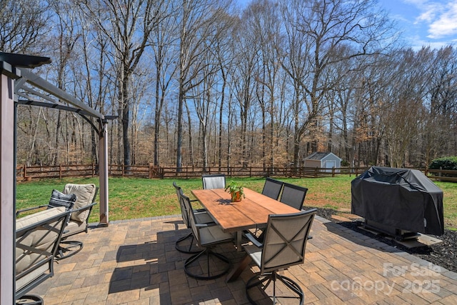 view of patio / terrace with an outbuilding, area for grilling, outdoor dining area, and a fenced backyard